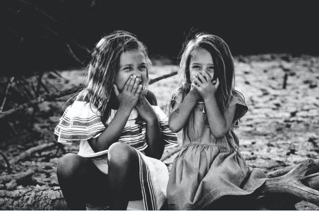 Zwei Mädchen halten sich die Hände vor dem Mund und lachen
