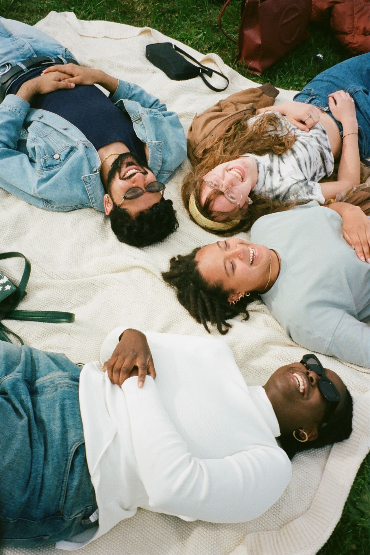 4 Freunde liegen auf einer Decke und lachen