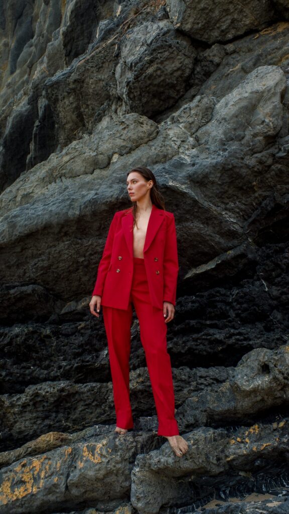 Frau im roten Anzug steht auf einem Felsen