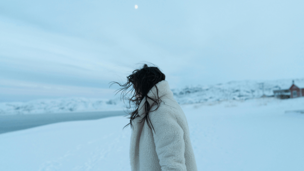 Frau in flauschiger Jacke vor Winterlandschaft