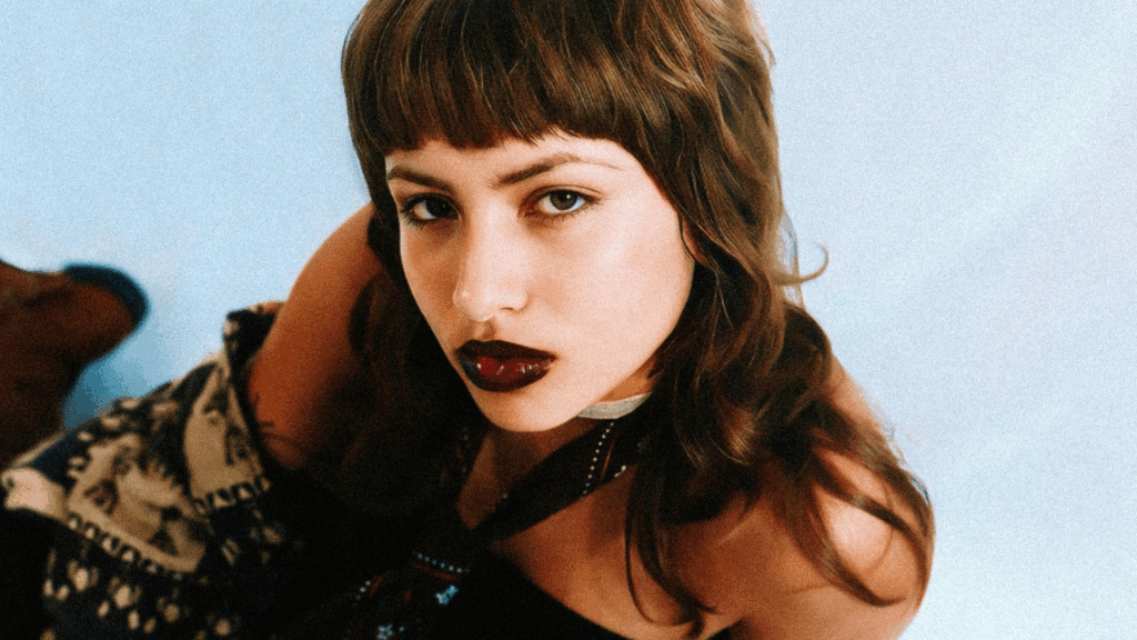 Frau mit dunkelroten Lippen und Mullet sitzt am Boden