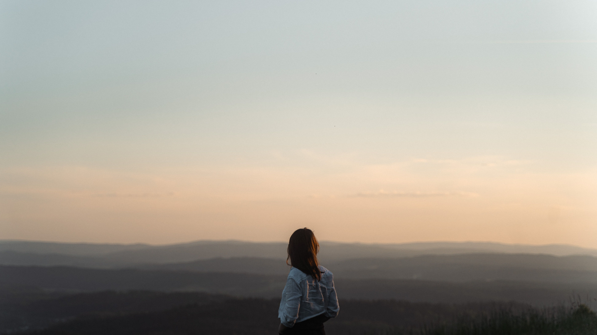Eine Frau blickt bei Sonnenuntergang über den Horizont