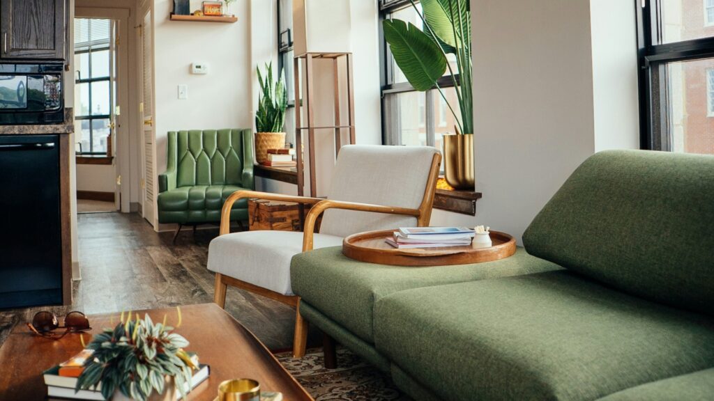 aufgeräumte Wohnung mit grünem Sofa, stylischen Stühlen, Pflanzen