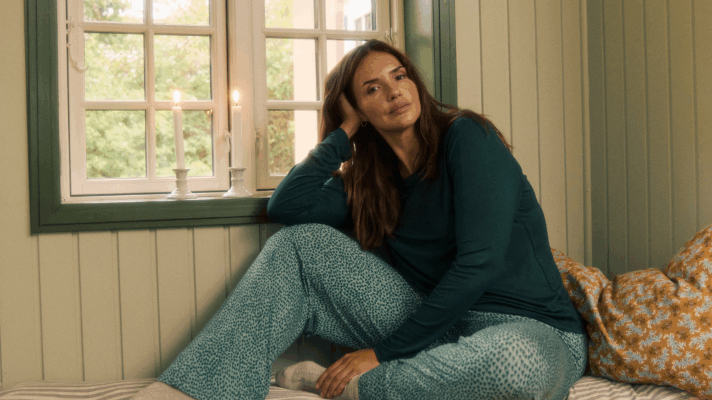 Frau im Pyjama vor einem Fenster